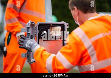 23. Juni 2021, Nordrhein-Westfalen, Sprockhövel-Haßlinghausen: Zwei Mitarbeiter von Straßen.NRW bauen auf dem Rathausplatz ein radarbasiertes Verkehrszählgerät. Derzeit findet in ganz Deutschland die Zählung des Straßenverkehrs statt. In jüngster Zeit setzt Straßen.NRW zu diesem Zweck zunehmend Radar- und videobasierte Methoden ein. Foto: Jonas Güttler/dpa Stockfoto