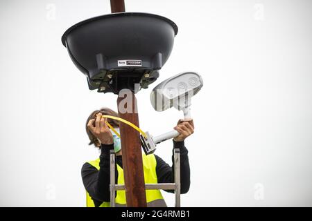 23. Juni 2021, Nordrhein-Westfalen, Sprockhövel-Haßlinghausen: Ein Mitarbeiter von Straßen.NRW montiert am Rathausplatz eine Kamera für videobasierte Verkehrszählungen. Derzeit findet in ganz Deutschland die Zählung des Straßenverkehrs statt. In jüngster Zeit setzt Straßen.NRW zu diesem Zweck zunehmend Radar- und videobasierte Methoden ein. Foto: Jonas Güttler/dpa Stockfoto