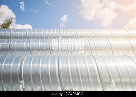 Lüftungsrohre gegen den blauen Himmel. Stahlrohre, Teile für den Bau von Luftkanälen für eine industrielle Klimaanlage in einem Lager Stockfoto