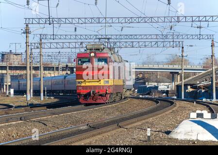 SHARYA, RUSSLAND - 10. APRIL 2021: Die tschechische Elektrolokomotive CHS-4t mit Personenzug fährt vom Bahnhof Sharya der Nordbahn ab Stockfoto