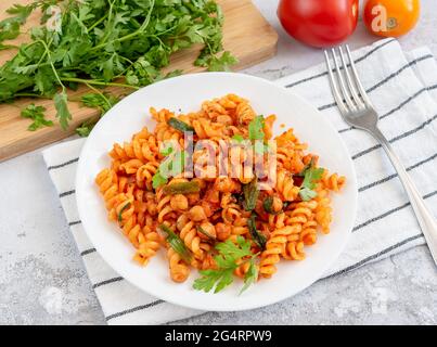 Fusilli-Pasta mit Kichererbsen und Tomaten- und Kräutersoße auf einem Servierteller Stockfoto