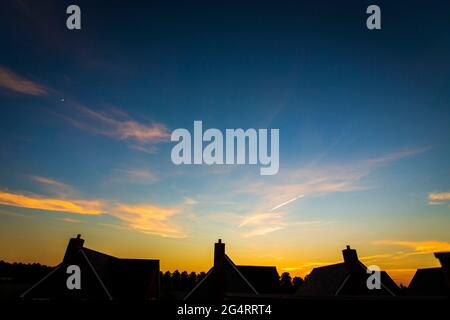 Die Sonnenuntergänge über den Dächern und die traditionellen Kamine neuer Häuser in Maidstone, Kent, Großbritannien. Stockfoto