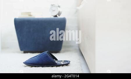 Blaue, weiche Hausschuhe auf weißem Teppich im Schlafzimmer Stockfoto