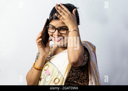 Eine wunderschöne indische Frau im Saree, die über ein Smartphone spricht und isoliert auf weißem Hintergrund lächelt Stockfoto
