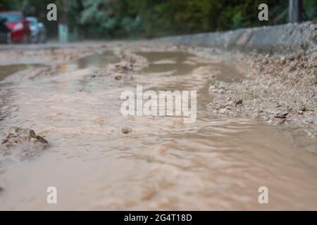 Schlammiges Wasser, das nach dem Regen aus den Straßen fließt. Stockfoto