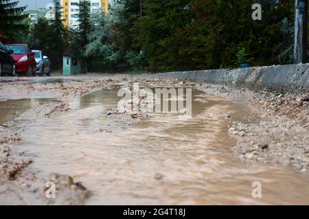 Schlammiges Wasser, das nach dem Regen aus den Straßen fließt. Stockfoto