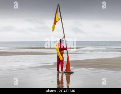 Garrettstown, Cork, Irland. Juni 2021. An einem grauen und bewölkten Tag legt der Rettungsschwimmer Dan O'Grady am Strand von Garrettstown, Co. Cork, Irland, eine Warnflagge für Schwimmer aus. - Credit; David Creedon / Alamy Live News Stockfoto