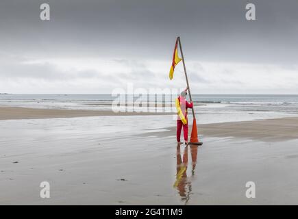 Garrettstown, Cork, Irland. Juni 2021. An einem grauen und bewölkten Tag legt der Rettungsschwimmer Dan O'Grady am Strand von Garrettstown, Co. Cork, Irland, eine Warnflagge für Schwimmer aus. - Credit; David Creedon / Alamy Live News Stockfoto