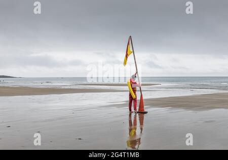 Garrettstown, Cork, Irland. Juni 2021. An einem grauen und bewölkten Tag legt der Rettungsschwimmer Dan O'Grady am Strand von Garrettstown, Co. Cork, Irland, eine Warnflagge für Schwimmer aus. - Credit; David Creedon / Alamy Live News Stockfoto