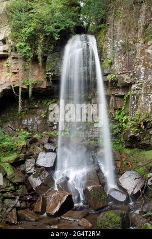 Melincourt Waterfalls, Neath, Wales, aufgenommen mit einer langsamen Verschlusszeit, um die Wasserbewegung zu zeigen, während es auf Felsen herunterstürzt Stockfoto