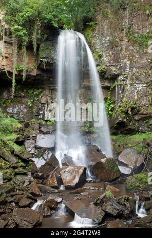 Melincourt Waterfalls, Neath, Wales, aufgenommen mit einer langsamen Verschlusszeit, um die Wasserbewegung zu zeigen, während es auf Felsen herunterstürzt Stockfoto