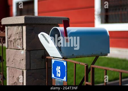 Direkt vor dem Gartentor befindet sich ein Briefkasten im alten Stil mit offenem Deckel. Mailbox Mit Selektivem Fokus Stockfoto