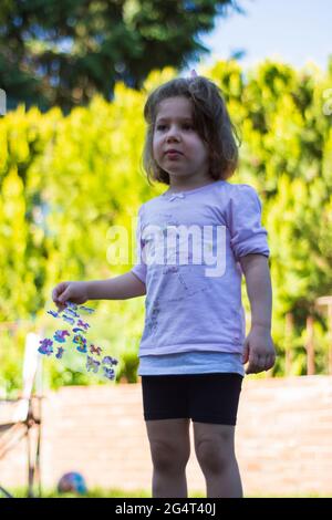 Das kleine Mädchen spielt mit Aufklebern im Garten Stockfoto