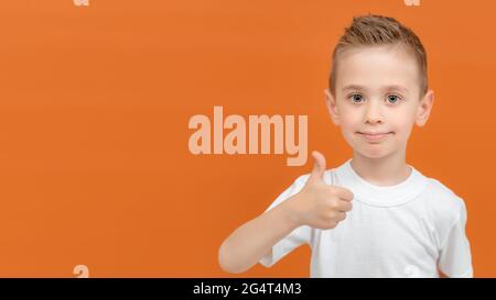 Banner-Porträt eines glücklichen Vorschulkinder zeigt Daumen nach oben Geste isoliert auf orangefarbenem Hintergrund. Platz für Ihren Text oder Ihr Produkt kopieren. Stockfoto