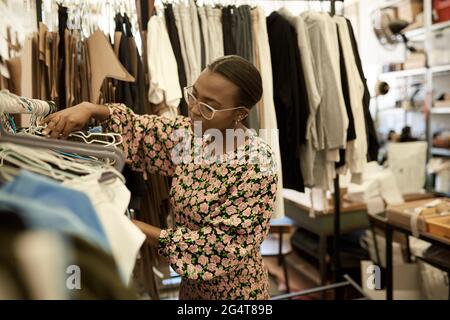 Afrikanische Modedesignerin, die in ihrem Studio Kleidung auf Racks ansieht Stockfoto