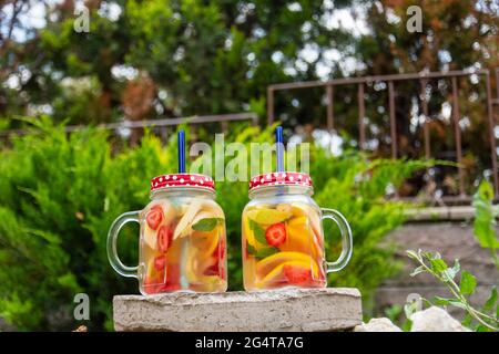 Zwei Glasröhren, köstliches Detox-Getränk mit roten, orangen und gelben Früchten, auf dem Stein stehend. Brille Mit Selektivem Fokus. Stockfoto