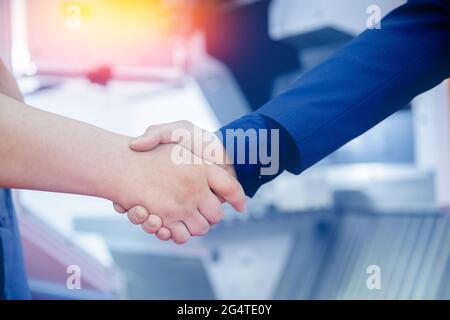 Arbeiter-Ingenieur schüttelt sich die Hände mit Geschäftsmann auf Baustelle Hintergrund cnc-Bedienfeld. Stockfoto