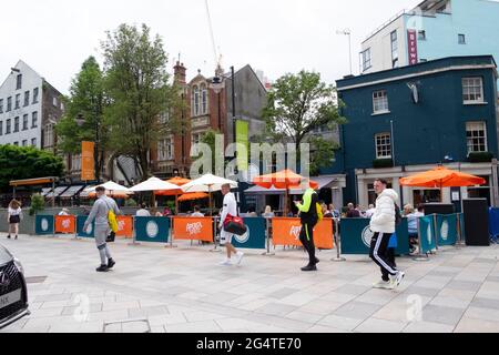 Junge Männer gehen an Tischen und Stühlen im Freien vorbei, um sich von draußen zu distanzieren. The Hayes in Cardiff City Centre Wales UK KATHY DEWITT Stockfoto
