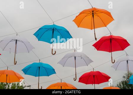 Bunte Regenschirme hängen beim Outdoor-Festival am bewölkten Himmel Stockfoto