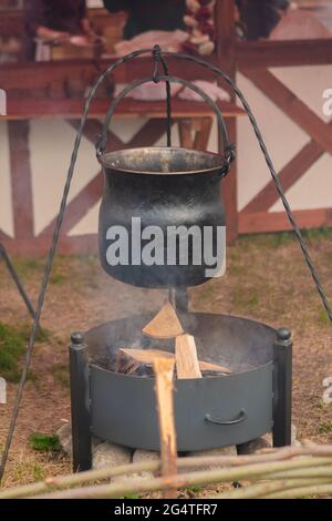 Essen im hängenden Topf über offenem Feuer zubereiten - Campingkonzept Stockfoto