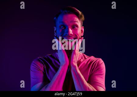 Portrait von attraktiven fröhlich erstaunt verrückt Kerl große Nachrichten Reaktion isoliert über dunklen Neon Licht violetten Hintergrund Stockfoto