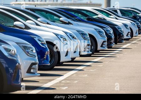 Eine Reihe nagelneuer Autos Reihen sich auf einem Parkplatz im Freien an. Stockfoto