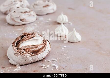 Schokolade wirbeln Baiser und Baiser Küsse auf einem rosa Marmor Hintergrund. Stockfoto