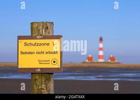 Watt- und Wattenmeer-Nationalpark-Schild vor dem Leuchtturm Westerhever im Frühjahr, Nordfriesland, Schleswig-Holstein, Deutschland Stockfoto