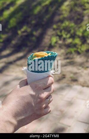 Mann, der an sonnigen Tagen farbige Eiskegel mit Mango-Eis im Inneren hält Stockfoto