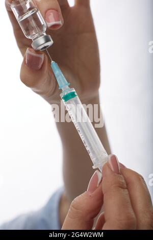 Ärztin in Gesichtsmaske Medizin wählt Impfstoff in Spritze auf weißem Hintergrund. Stockfoto