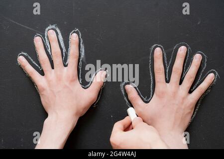 Hand halten Stück Kreide und ziehen Sie einen Kreis der anderen Hand Stockfoto