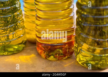 Eine Reihe von aromatischen goldenen Olivenölen, angereichert mit würzigem Chili und mediterranen Kräutern Stockfoto