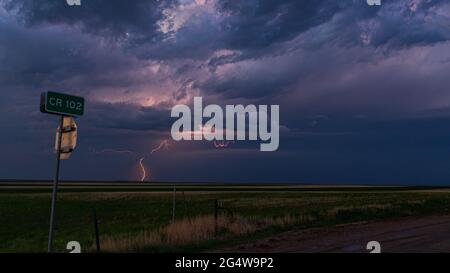 Blitzschlag schlägt in der Ferne ein und beleuchtet einen dunklen und bedrohlichen Himmel, während ein Gewitter durch den Osten Colorados zieht Stockfoto