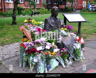 Blumen umgeben die Alan Turing Statue und das Denkmal, Sackville Gardens, Manchester, England, Großbritannien, Vereinigtes Königreich, am 23. Juni 2021, dem Jahrestag von Turing's Geburtstag. Alan Mathison Turing OBE war ein englischer Mathematiker, Informatiker, Logiker und Kryptanalyst. Im 2. Weltkrieg leitete er ein Team, das dafür verantwortlich war, deutsche Cipher der Enigma-Maschine zu brechen. Turing hatte damals Einfluss auf die Entwicklung der Informatik an der University of Manchester. Stockfoto