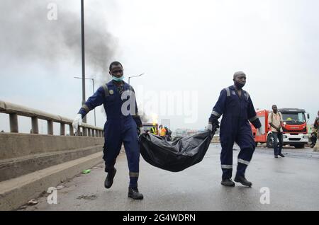 Men of Lagos State Emergency Management Agency, die die Überreste eines verbrannten Tanker-Lkw-Fahrers nach einer Gasexplosion mit vier Gelenkfahrzeugen auf dem Abschnitt der Kara-Brücke der Lagos-Ibadan-Schnellstraße transportiert. Nigeria. Stockfoto