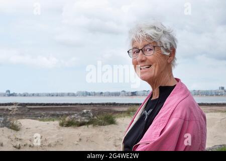 Eine ältere Frau geht am Strand in der Bretagne spazieren Stockfoto