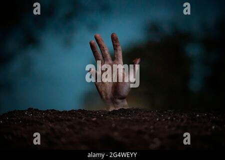 Schmutzige Person Zombie tot Mann Hand heben aus dem Boden, Horror-Konzept Stockfoto