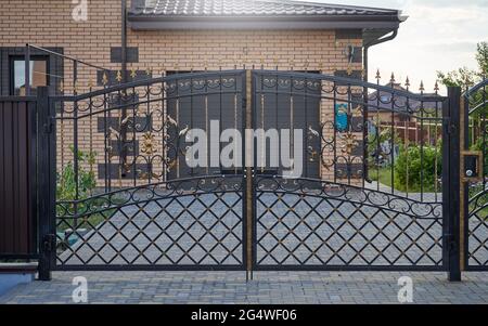 Vor dem Eingang zur Garage stehen transparente, aus Metall geschmiedete Tore Stockfoto