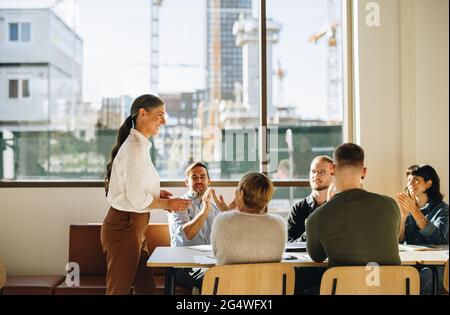 Weibliche Geschäftsführerin erhält nach einer Präsentation positives Feedback von ihrem Team. Stockfoto