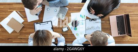 Gruppe von Leuten, die am Tisch sitzen und ihre Köpfe halten Draufsicht Stockfoto