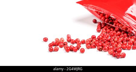 Rosafarbene Pfefferkörner - getrocknete Früchte aus peruanischem peppertree ( Schinus molle ), mit roter Plastikverpackung in der Nähe, Nahaufnahme Detail von oben Stockfoto