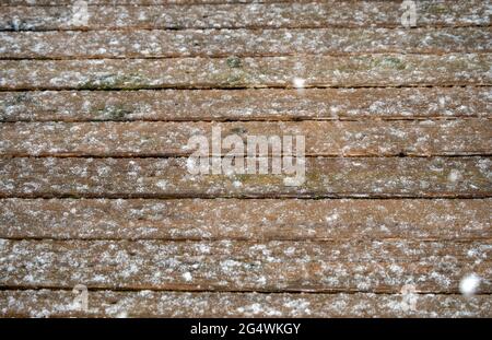 Fallende Schneeflocken machen an einem Wintertag auf dem Hinterhof-Deck im Südwesten von Missouri ein hübsches Spritzmuster. Der Schnee fiel immer noch unter diesem ph-wert Stockfoto