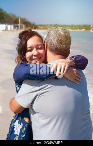Reifes Paar umarmt und schlendert am Strand Stockfoto