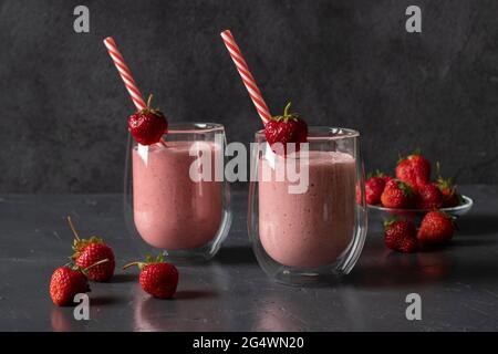 Indische Erdbeer Lassi oder Smoothie auf dunkelgrauem Hintergrund. Traditionelles ayurvedisches gesundes Getränk mit Erdbeeren Joghurt und Eiswürfel in zwei Gläsern Stockfoto