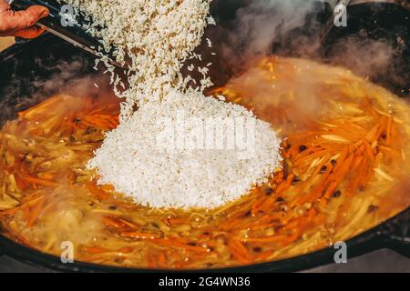 Duftender, köstlicher Pilaf mit frischem Gemüse und Fleisch. Festliche, frisch zubereitete Speisen auf der Straße. Konzept Grill, Grill, Essen im Freien Stockfoto