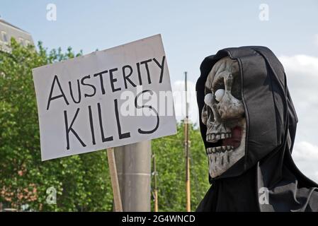 Ein maskierter Anti-Austeritäts-Demonstrator hält am 8. Juli 2015 in Bristol, Großbritannien, ein Plakat mit dem Slogan „AUSTERITÄTS-KILLS“ Stockfoto