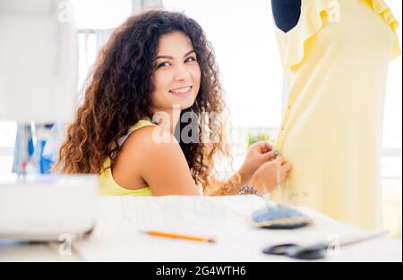 Lächelnder Schneider pinning Teile des Kleides in der Werkstatt Stockfoto