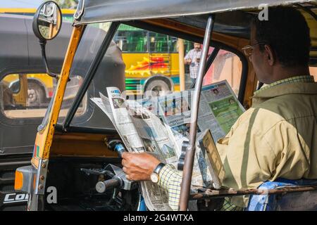 Der indische Auto-Rikscha-Fahrer in Khaki-Uniform sitzt in der Taxi-Zeitung Udupi, Karnataka, Indien Stockfoto