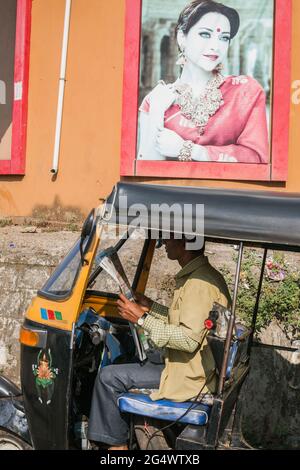 Der indische Auto-Rikscha-Fahrer in Khaki-Uniform sitzt in der Taxi-Zeitung Udupi, Karnataka, Indien Stockfoto