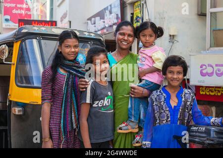 Die attraktive indische Mutter und ihre liebevollen vier Töchter posieren für Familienfotos auf der Straße neben der Auto-Rikscha, Mysore, Karnataka, Indien Stockfoto